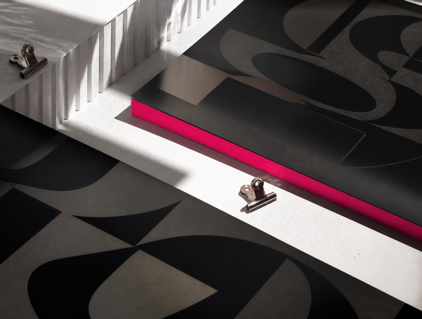 Black editorial identity materials with a bright magenta edge in studio light